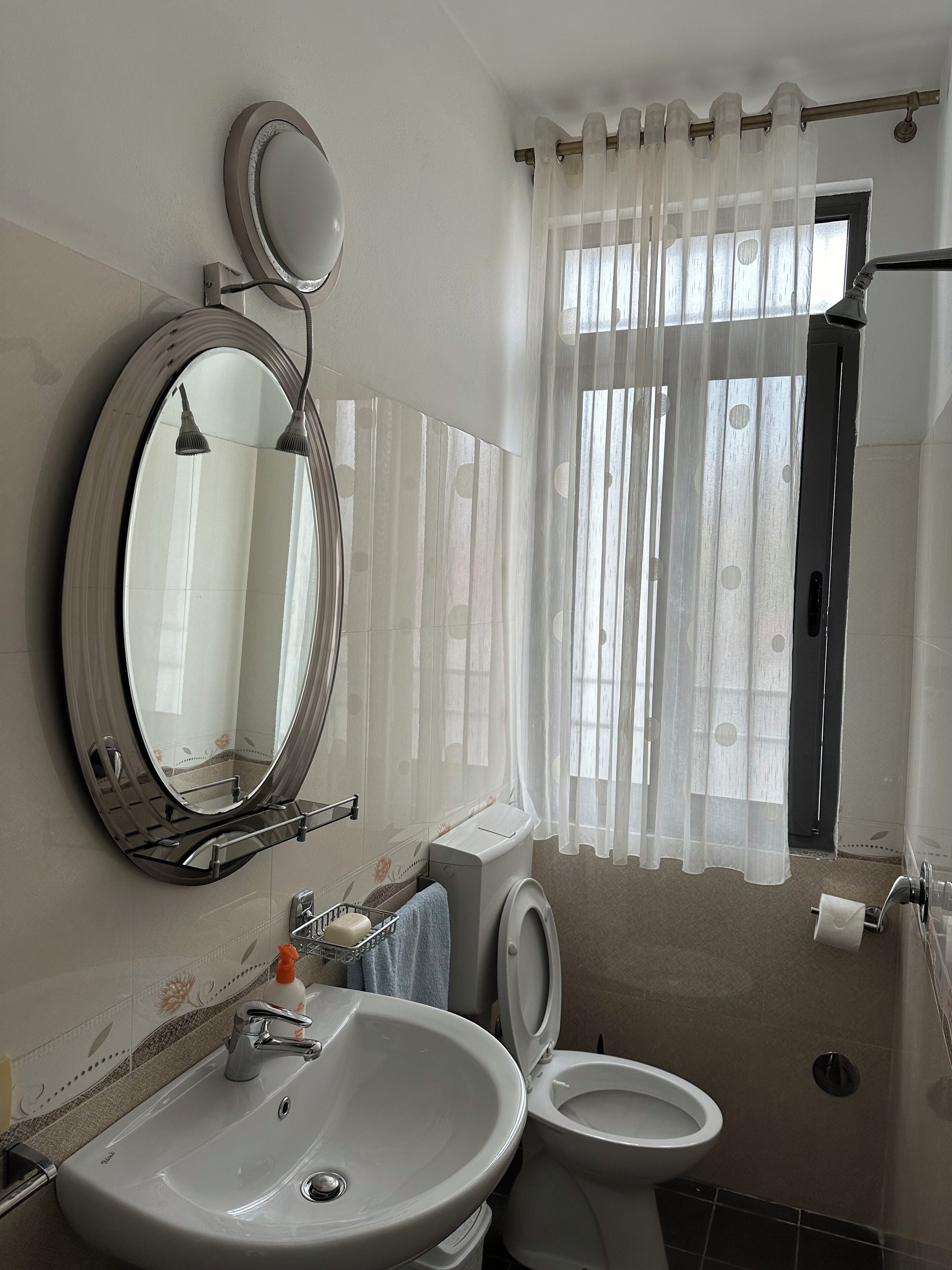 A bathroom with a sink, mirror, toilet, and shower curtain.