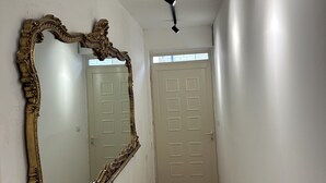 Un couloir doté d’un plancher en bois, d’un grand miroir décoratif et d’une porte ornée d’un motif géométrique.