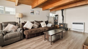 A cozy living room with a leather sofa, a wooden coffee table, and a fireplace. - PureSky Cabin (Big Bear City)
