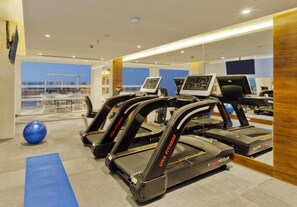 Ein Fitnessraum mit Laufbändern, Übungsbällen und einer blauen Matte.