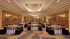 A large banquet hall with round tables, black chairs, and a patterned carpet. - Country Inn Premier Amritsar (Amritsar)