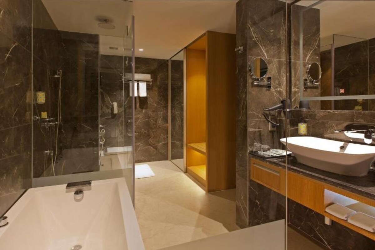 Un baño moderno con una bañera grande, una ducha con mampara de vidrio y un lavamanos con lavabo y espejo.