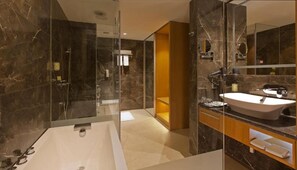 Un baño moderno con una bañera grande, una ducha con mampara de vidrio y un lavamanos con lavabo y espejo.