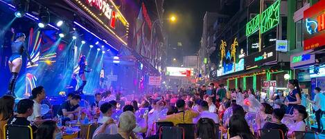 A crowded street with a stage and bright lights, suggesting a public event or performance.