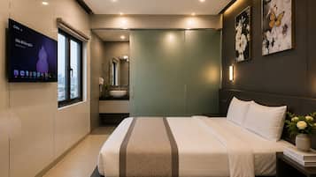 A modern hotel room with a bed, a TV, a bathroom, and artwork on the walls.