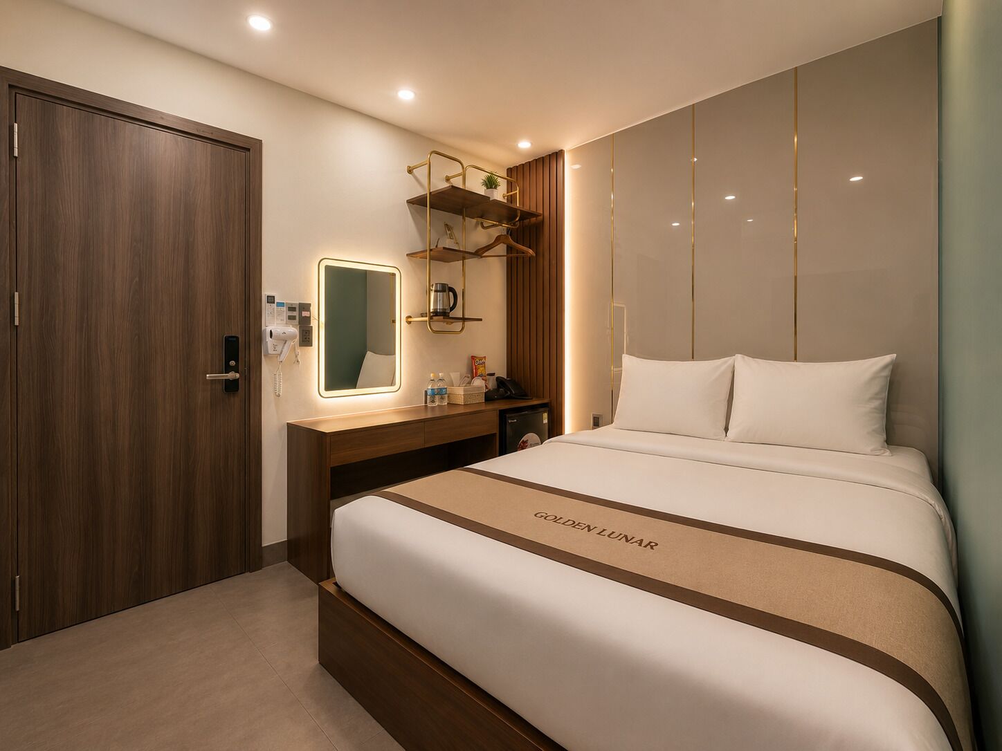 A hotel room with a large bed, a wooden wardrobe, a vanity with a mirror, and a shelf with toiletries.