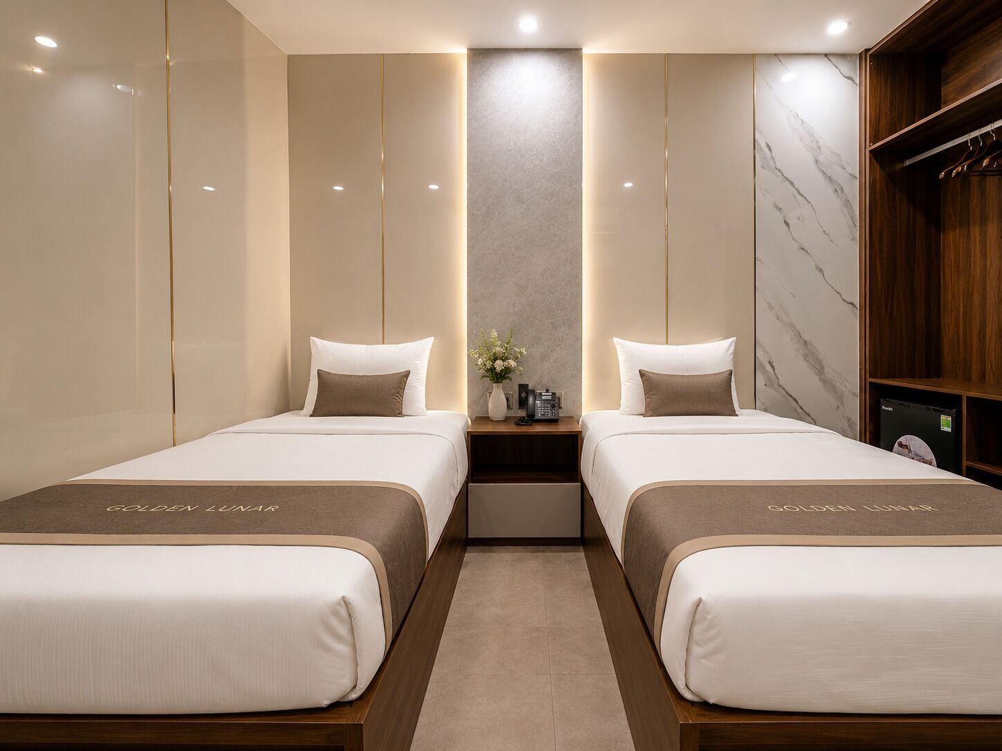 Une chambre d’hôtel avec deux lits, un mur en marbre, une armoire en bois et une table de chevet avec un téléphone.