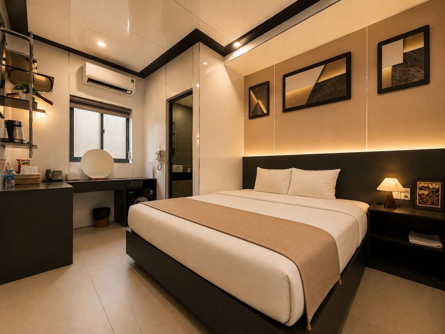 Ein modernes Hotelzimmer mit einem großen Bett, Nachttischen, einem Schreibtisch mit Stuhl, einer Klimaanlage und Kunstwerken an den Wänden.