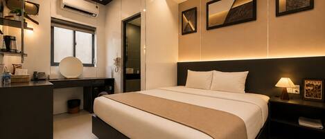 Ein modernes Hotelzimmer mit einem großen Bett, Nachttischen, einem Schreibtisch mit Stuhl, einer Klimaanlage und Kunstwerken an den Wänden.