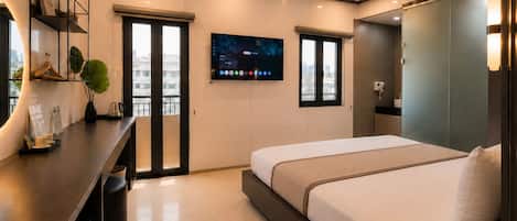 A modern hotel room with a bed, bedside table, a desk with a chair, a TV mounted on the wall, and a window with a view of the city.
