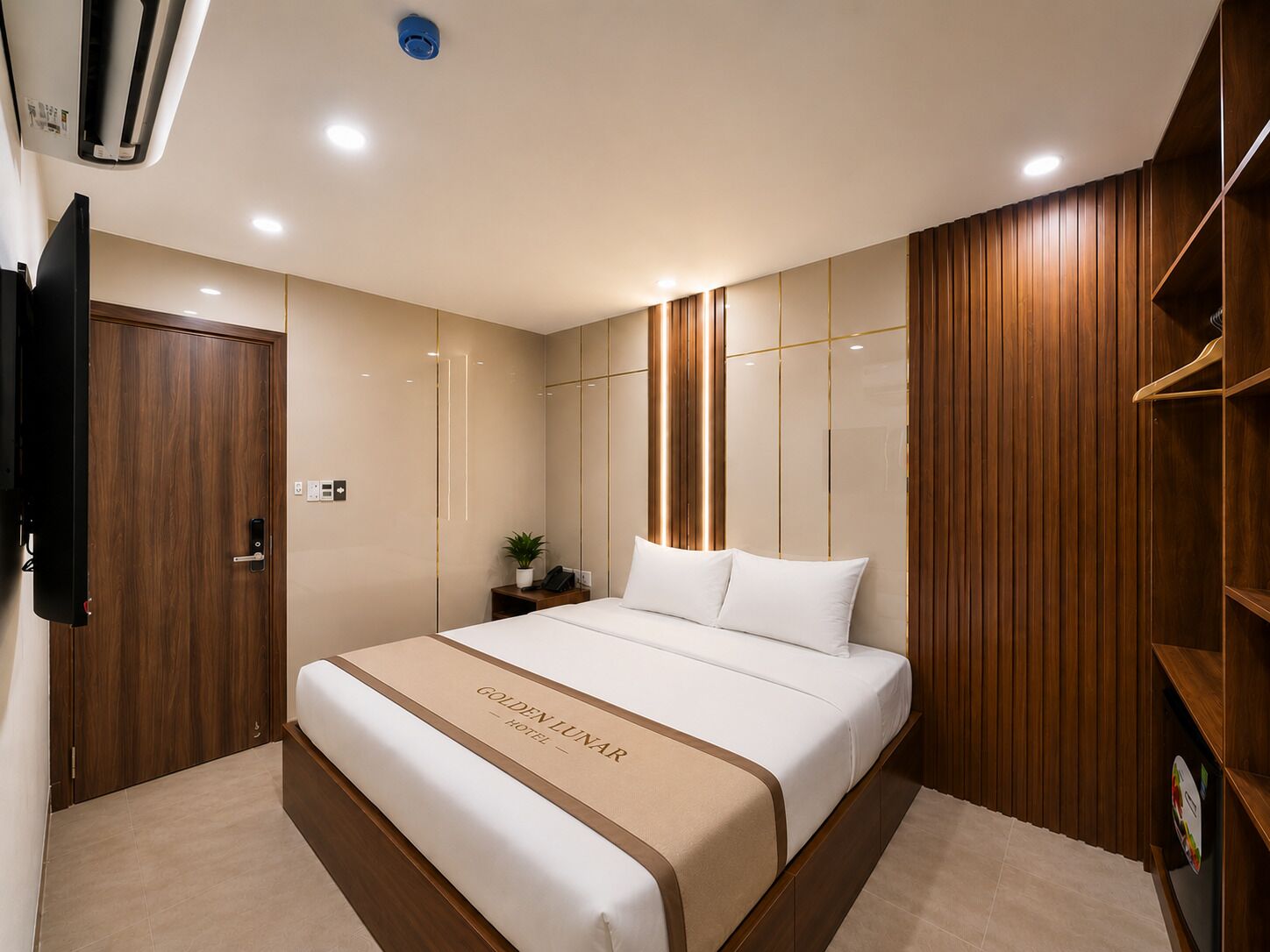 Ein Hotelzimmer mit Bett, Nachttisch, Fernseher, Kleiderschrank und einer Wand mit Holzverkleidung.