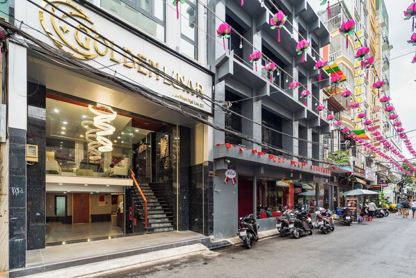 A hotel with a prominent sign, a staircase leading to the entrance, and parked motorcycles outside. - Golden Lunar (Ho Chi Minh City)