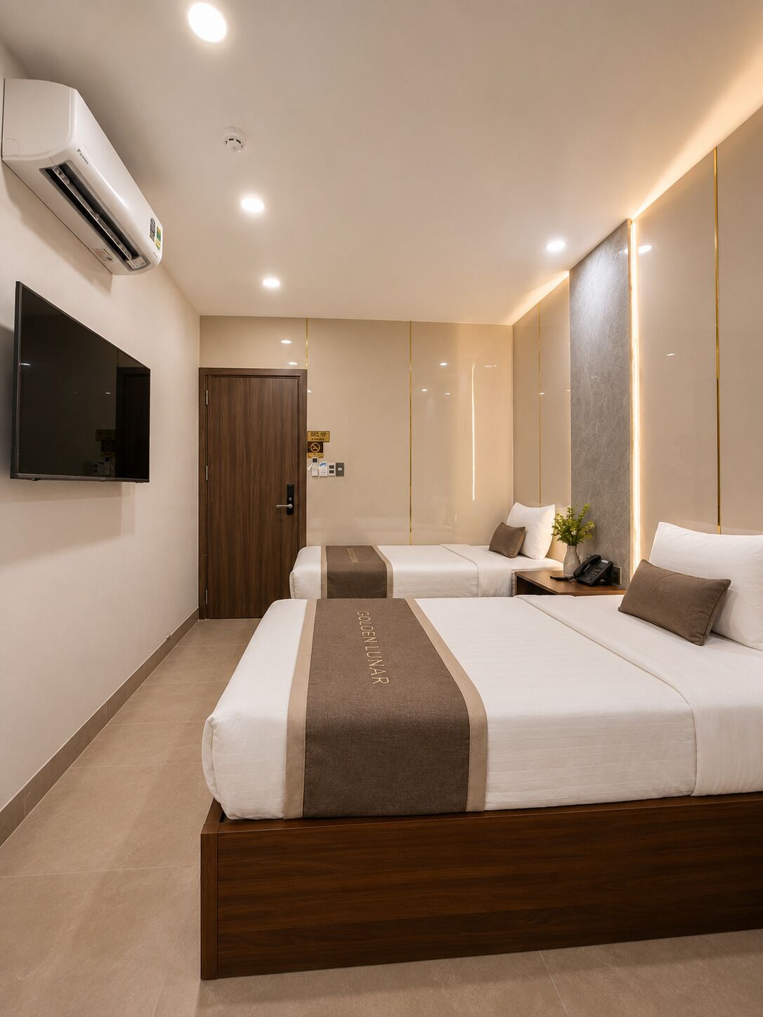 Una habitación de hotel con dos camas, un televisor, aire acondicionado y una puerta.