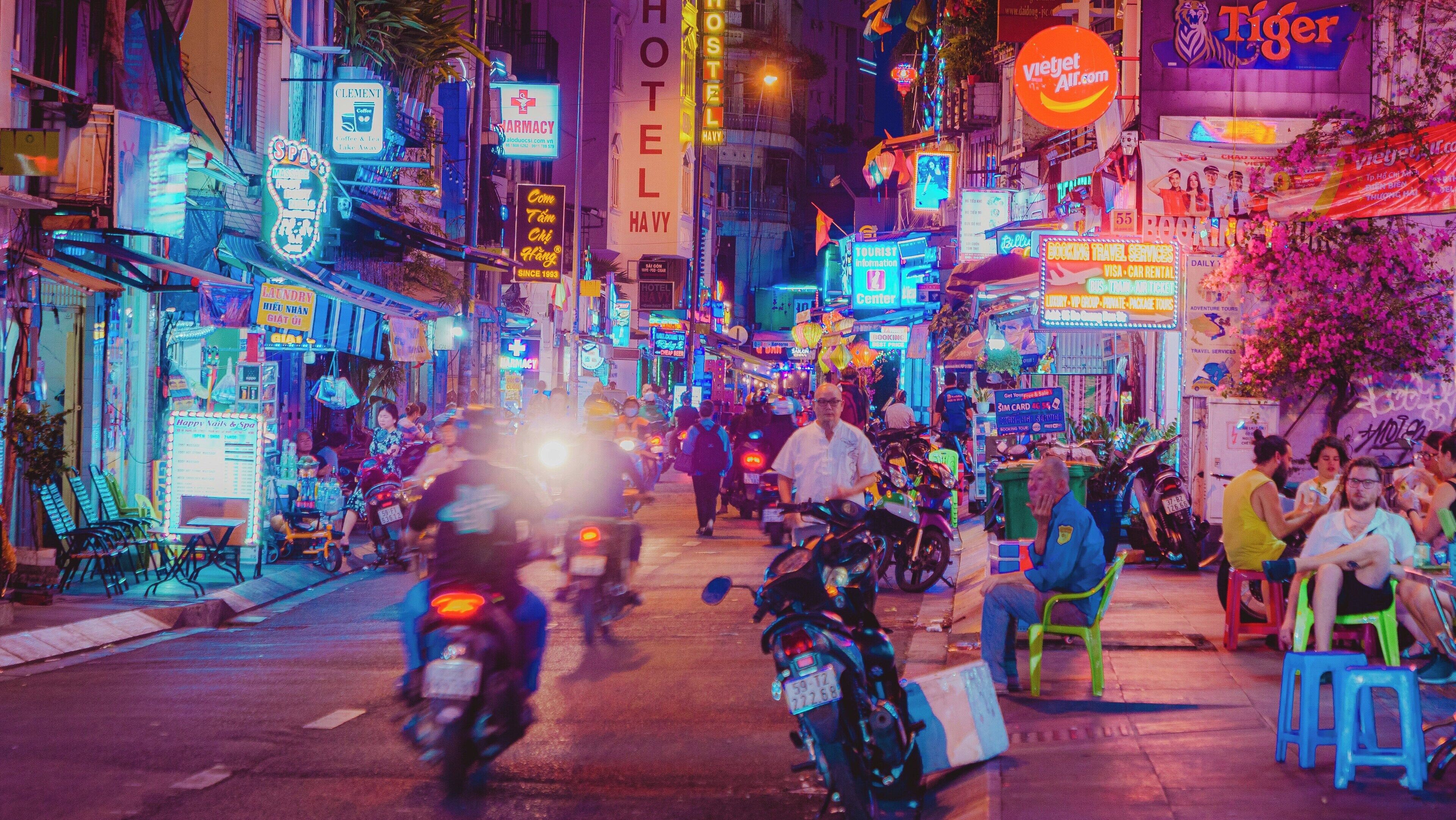 Eine belebte Straße mit Neonreklamen, einem Hotel und verschiedenen Geschäften.