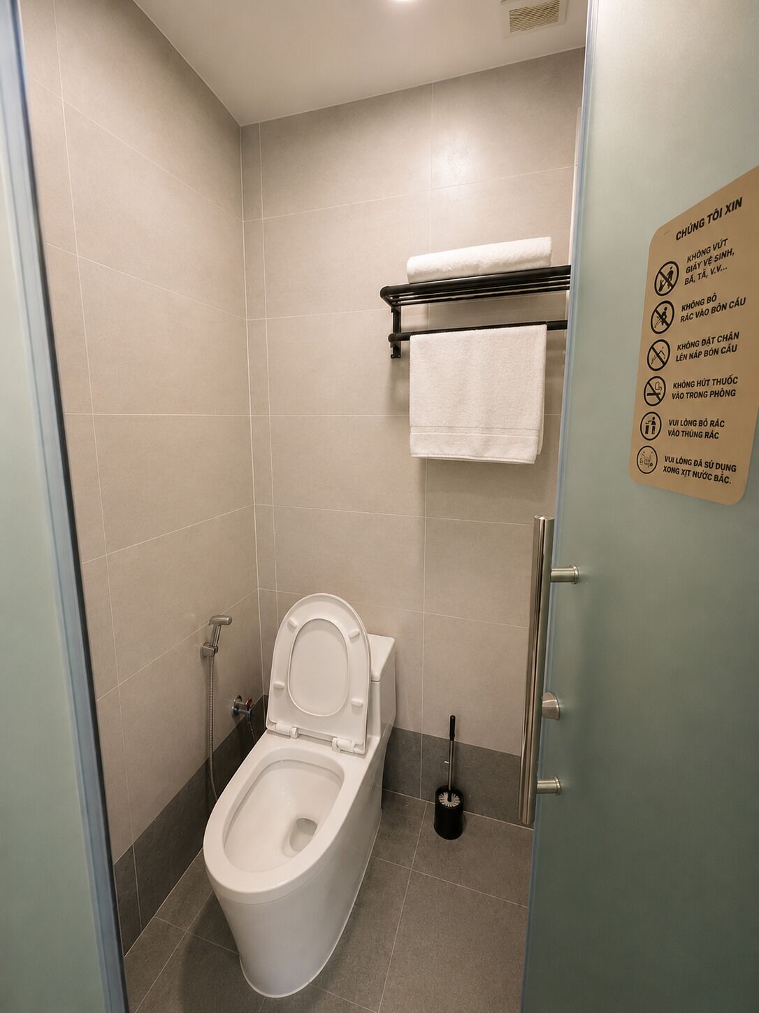 A modern bathroom with a toilet, a towel rack, and a sign with instructions.