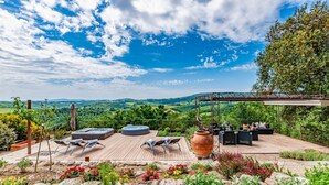 A wooden deck with outdoor seating, a pergola, and a view of the countryside.