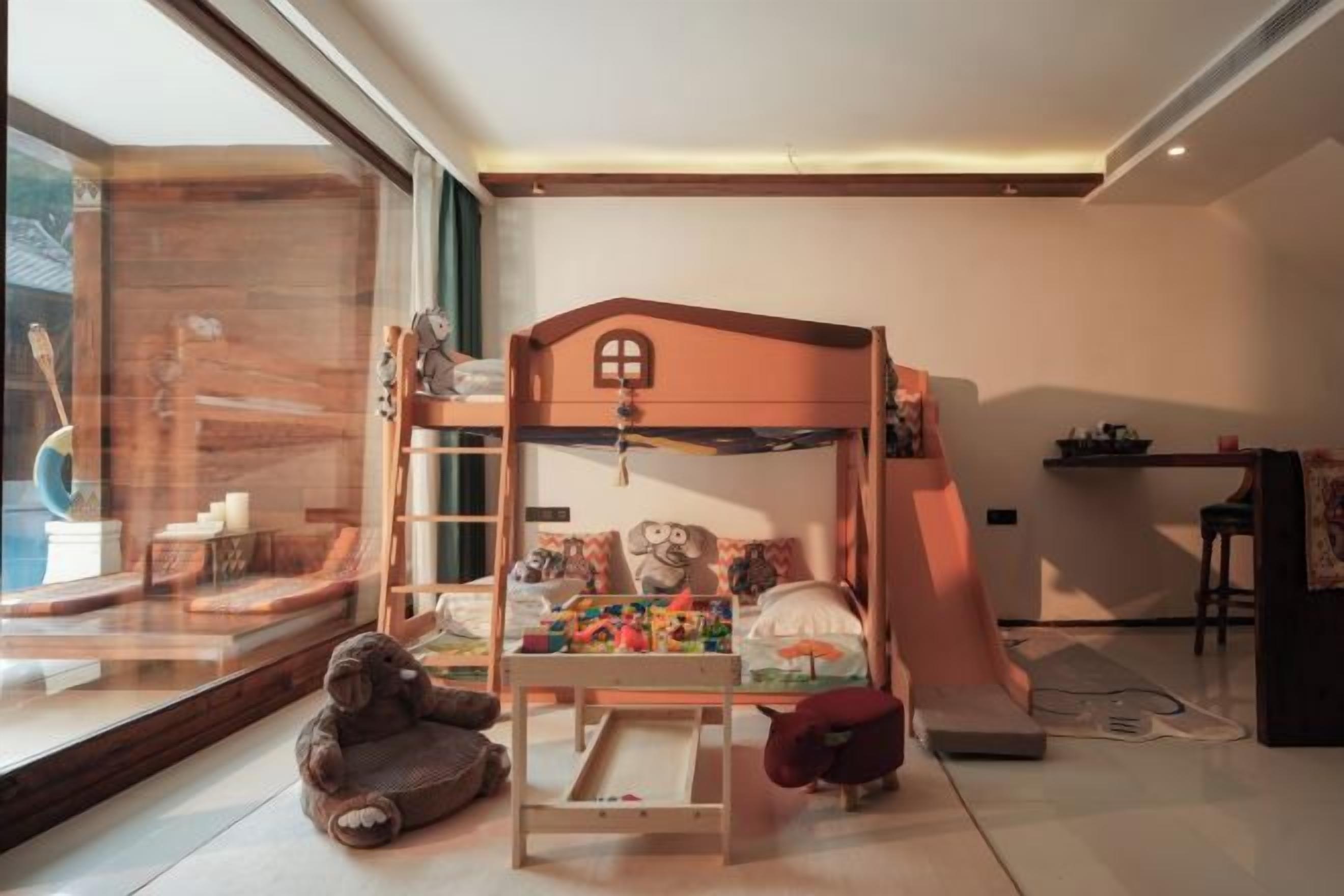A child's bunk bed with toys, a window view, and a small table.