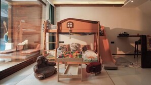 A child's bunk bed with toys, a window view, and a small table. - Jinghong Manying Dai Tai Courtyard Villa (Jinghong)