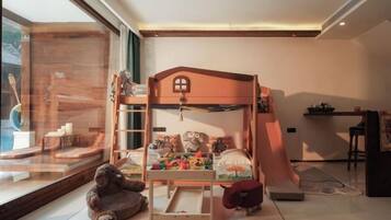 A child's bunk bed with toys, a window view, and a small table.