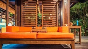 A wooden deck with a wooden sofa and a small table. - Jinghong Manying Dai Tai Courtyard Villa (Jinghong)