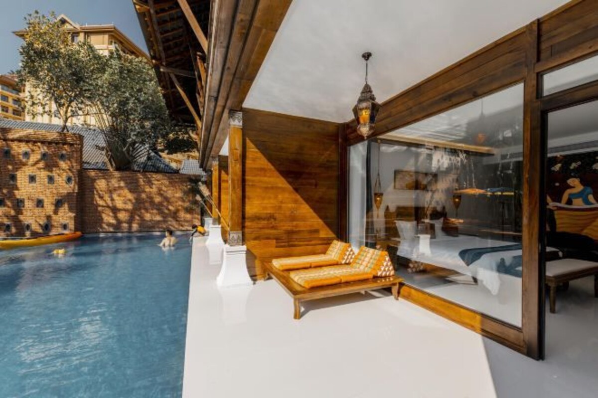 A modern pool area with wooden loungers and a glass wall.