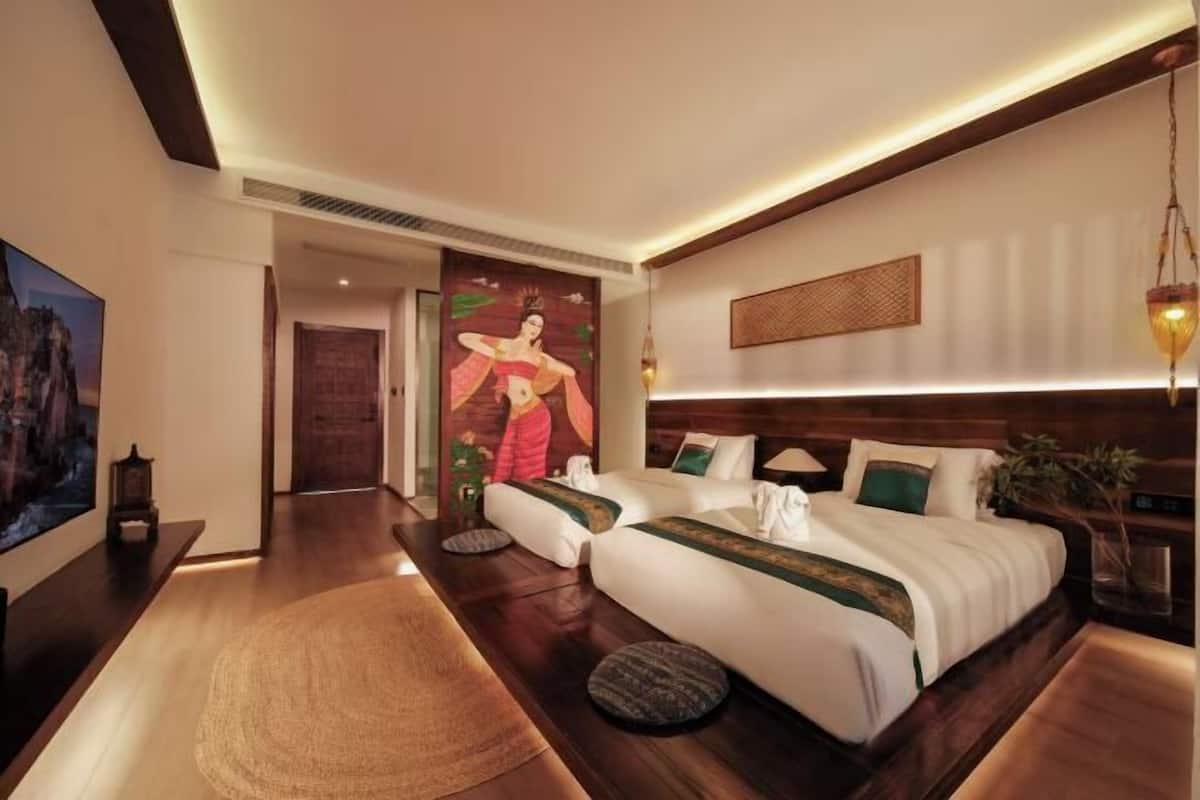 A modern hotel room with a large bed, a small sofa, a wooden floor, and a painting on the wall.