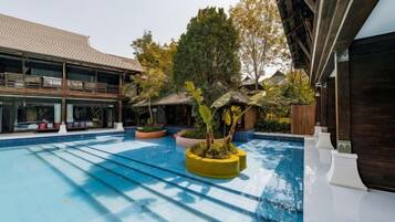 A swimming pool with a sunken area, surrounded by potted plants and seating areas.