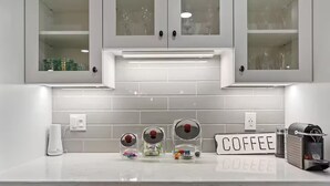 Eine moderne Küche mit weißen Schränken, einer Kaffeestation und einer Kaffeemaschine.