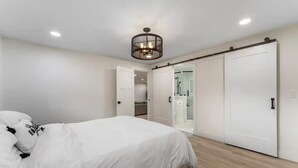 Ein Schlafzimmer mit einem Bett, einem Kleiderschrank und einem durch eine geöffnete Tür einsehbaren Badezimmer.
