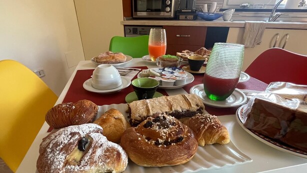 A breakfast table with pastries, a coffee pot, and a green drink. - Domus Joannina B&B (Pompei)