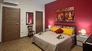 A bedroom with a bed, two bedside tables with lamps, a chair, a wardrobe, and an air conditioning unit. - Domus Joannina B&B (Pompei)