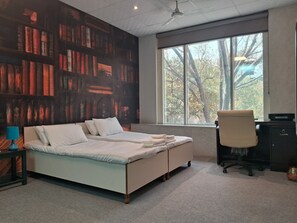 A bedroom with a large bed, a desk, and a chair. There is a window with a view of trees. - Stylish and Cosy Studio with huge window view, close to Moolchand Metro Station (New Delhi)