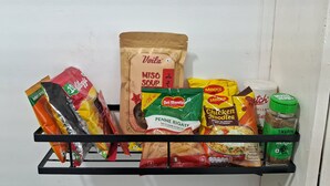 A shelf with various food items including a bag of miso soup, pasta, and packaged noodles. - Stylish and Cosy Studio with huge window view, close to Moolchand Metro Station (New Delhi)