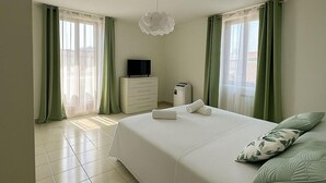 Ein Schlafzimmer mit einem Bett, einem Fernseher auf einer Kommode und einem Heizgerät auf dem Boden.