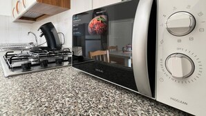 Eine moderne Küche mit Einbau-Mikrowelle, Gasherd und Kaffeemaschine.