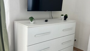 Ein weißer Kommode mit Schubladen und ein flachbildfernseher darüber montiert.