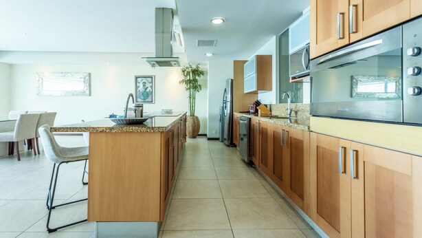 Una cocina moderna con armarios de madera, electrodomésticos de acero inoxidable y una isla central.