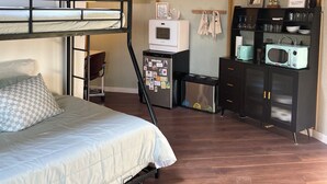 Ein kleines Zimmer mit Etagenbett, Küchenzeile und Holzboden.