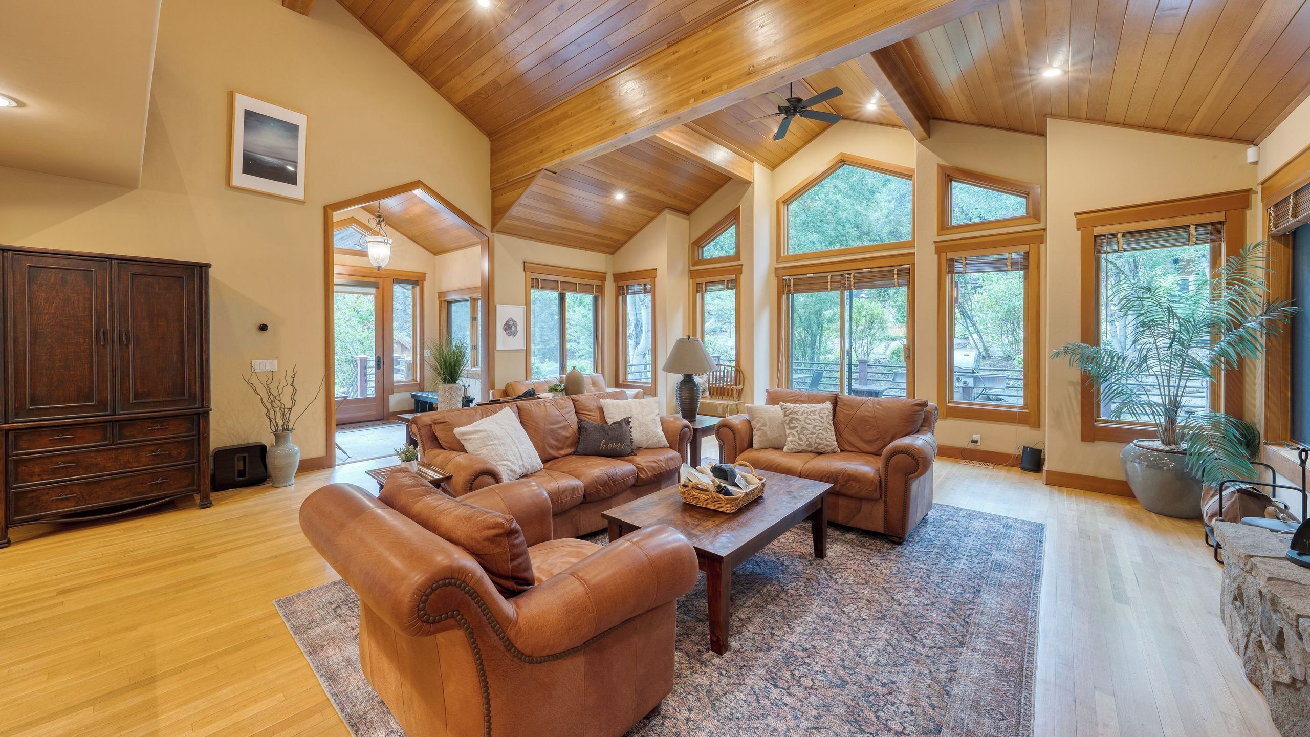 A spacious living room with a high ceiling, large windows, and a fireplace.