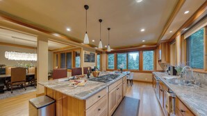 A modern kitchen with wooden cabinets, a large island, and pendant lighting. - Cedars at Palisades by Avantstay Hot Tub, Resort Access, and Mountain Views (Olympic Valley)