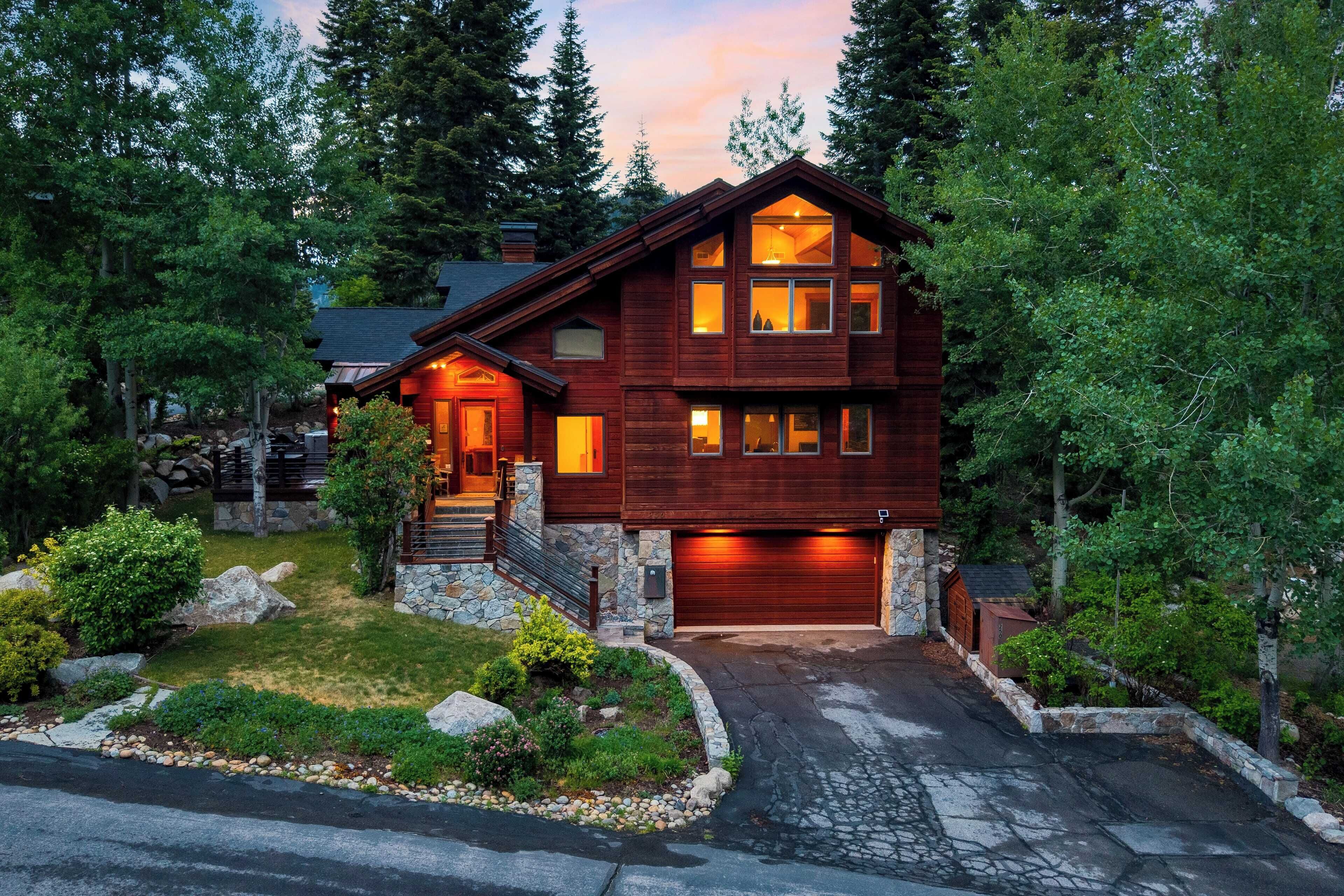 A two-story wooden house with a stone foundation, a garage, and a driveway leading to the entrance.