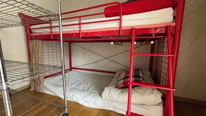 Ein rotes Etagenbett mit einer Metallleiter, Ablagefläche aus Metall und einem Vorhang.