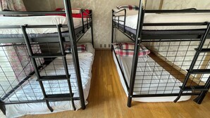 Ein Zimmer mit Stockbetten, Holzboden und einem blumigen Vorhang.