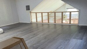 Una habitación amplia con techo inclinado y ventanas grandes.