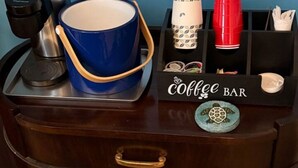 Un coin café aménagé avec une tasse bleue, une machine à café et un plateau contenant diverses tasses et une tasse à café.