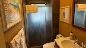 Une petite salle de bain comprenant une douche, des toilettes et un lavabo.