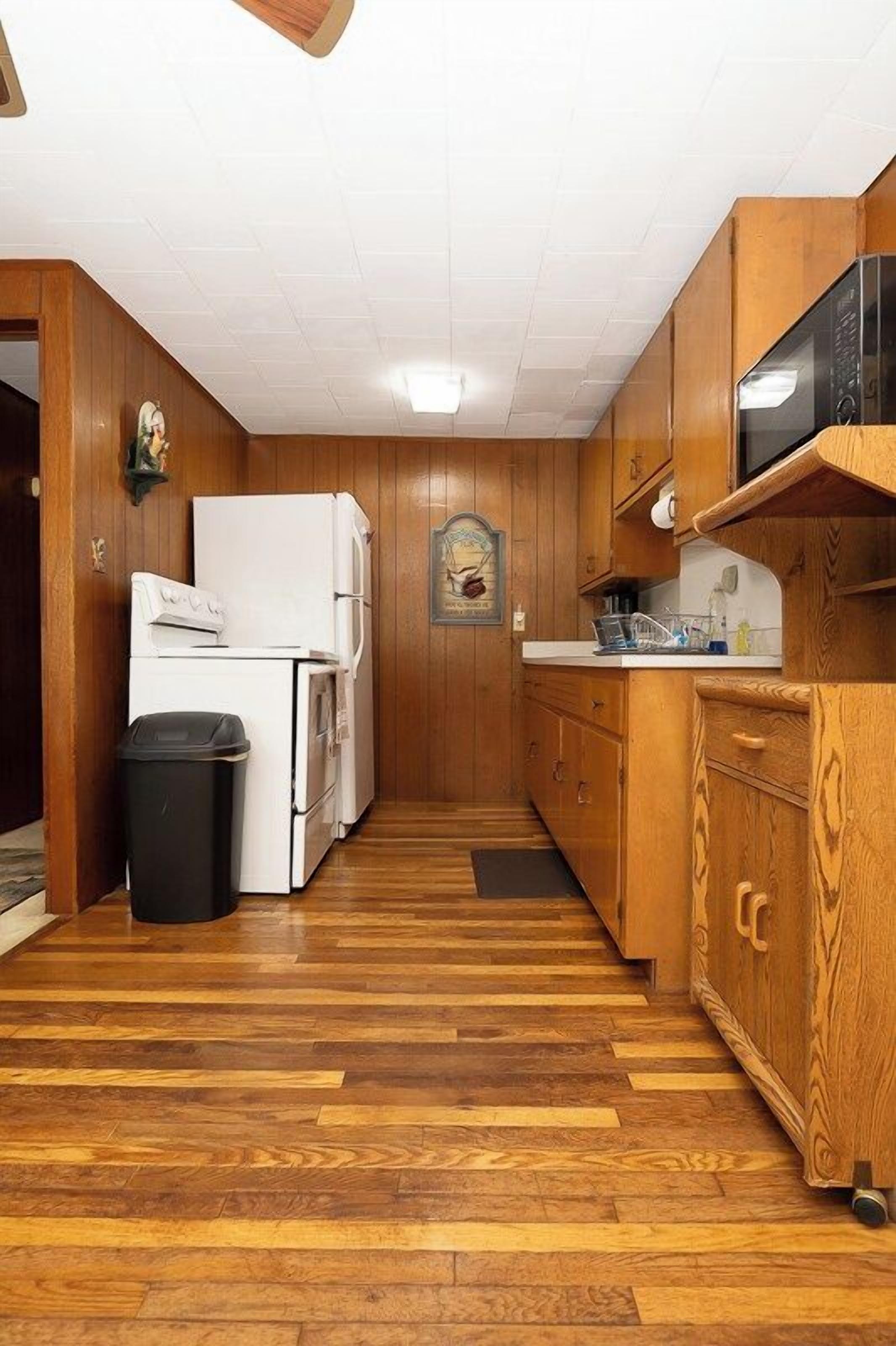 A kitchen with wooden cabinets, a white refrigerator, and a microwave on a wooden countertop.