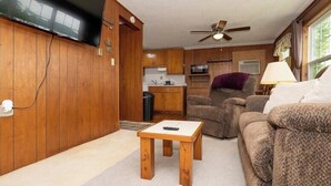 A wooden-paneled living room with a television, a ceiling fan, and a sofa. - The Cabin at Prairie Hollow Camp w/ Boat Slip* (Roach)