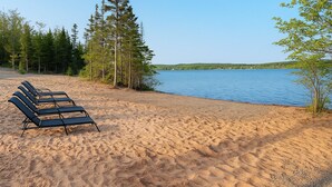 Ein Strand mit Liegestühlen und einem stillen See.