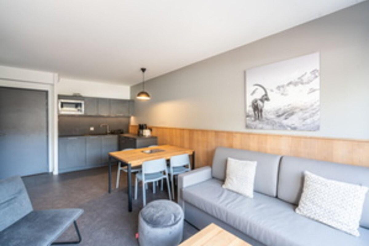 A modern living space with a sofa, a dining table, and a kitchen area.